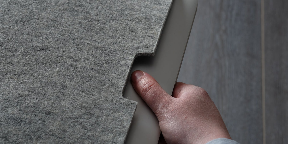 Grey wool felt MacBook sleeve, a MacBook Air being slid in by hand